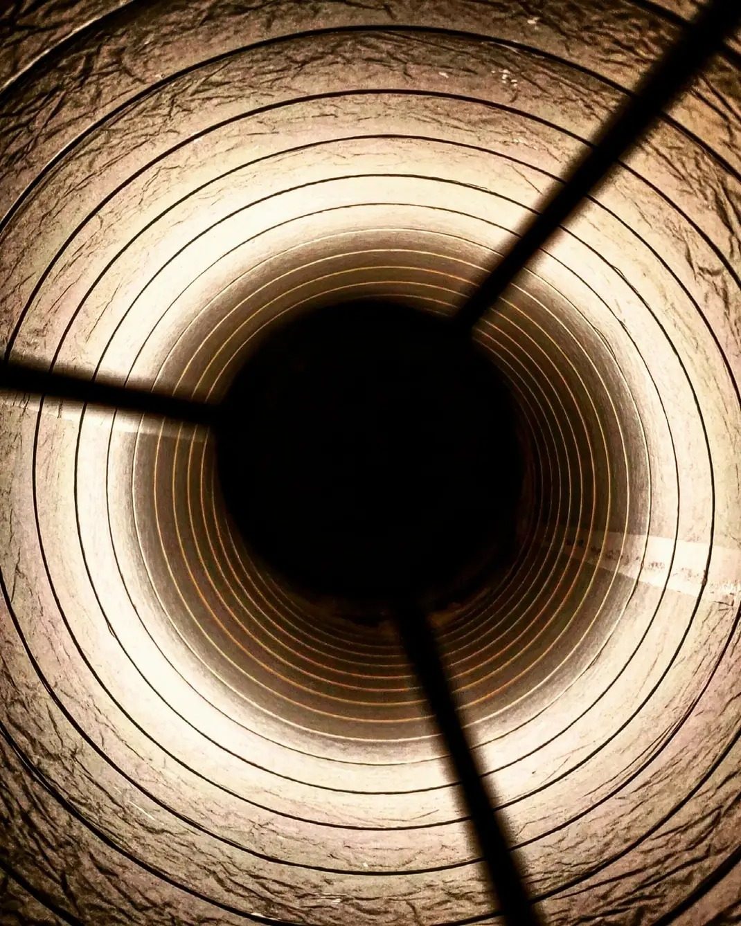 A macro photograph of warm amber material, concentric rings drawing inward toward a dark centre.